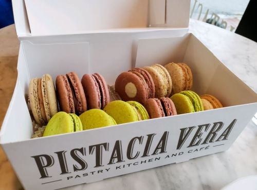 A box of colorful macarons in various flavors, displayed neatly from Pistacia Vera pastry kitchen.