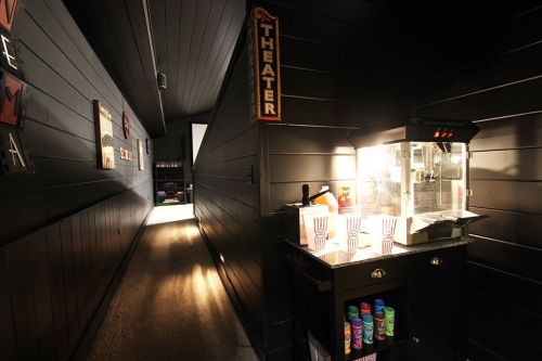 A dimly lit hallway leading to a home theater, featuring a popcorn machine and colorful snack containers.