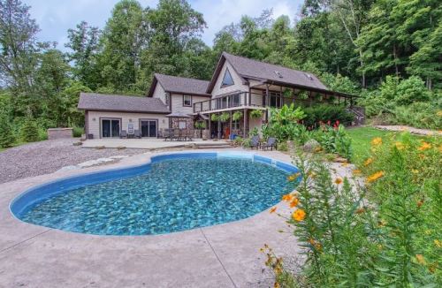 A scenic backyard with a heart-shaped pool, surrounded by lush greenery and a modern house in the background.