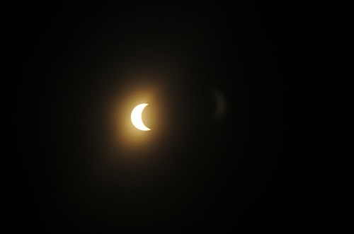 A partial solar eclipse with a crescent-shaped sun partially obscured against a dark background.