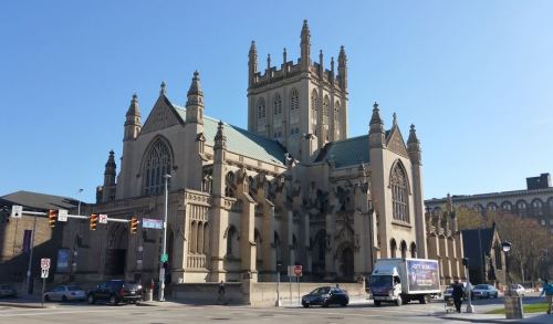 A large, ornate church with gothic architecture, featuring tall spires and intricate stonework against a clear blue sky.