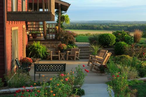 A cozy patio with wooden chairs, surrounded by colorful flowers and a scenic view of rolling hills in the background.