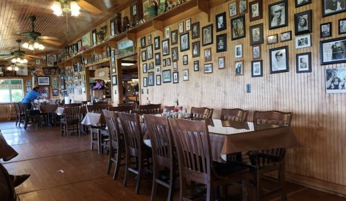 A cozy restaurant interior with wooden tables, chairs, and walls adorned with numerous framed photographs.