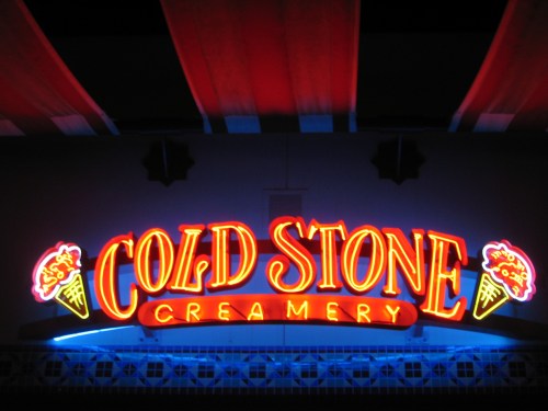 Neon sign for Cold Stone Creamery featuring colorful ice cream cones and bright lettering.