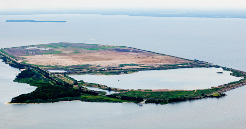 Aerial view of a large, flat island surrounded by water, featuring green areas and a barren section.