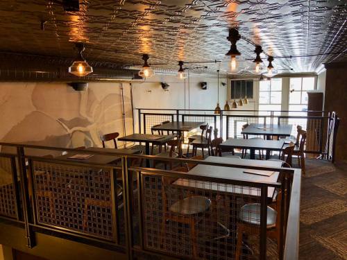 A cozy restaurant interior featuring wooden tables, chairs, and industrial-style lighting in a warm atmosphere.