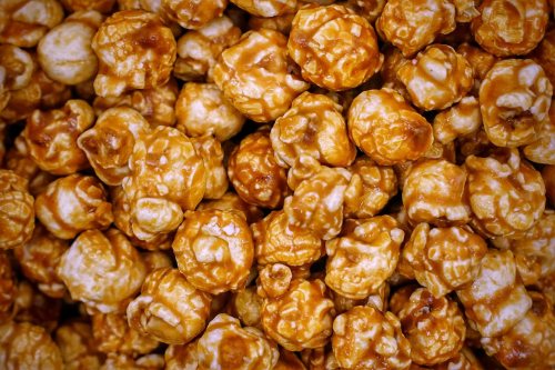 A close-up of caramel popcorn, showcasing a mix of golden and light brown coated kernels.