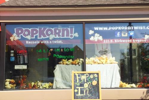 A storefront window displaying "PopKorn!" with colorful signs and popcorn for sale.