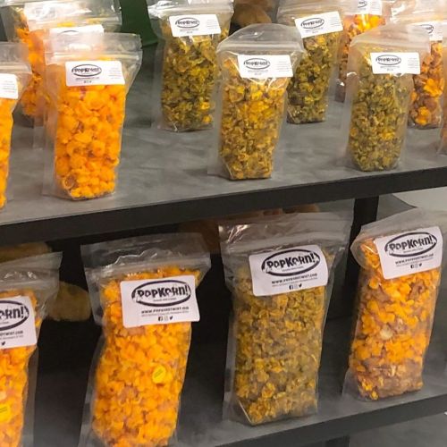 Bags of colorful popcorn in various flavors displayed on a shelf.