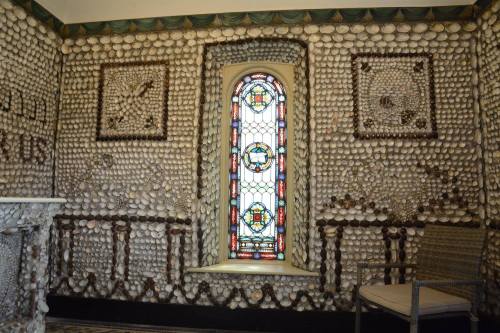 A room decorated with shells on the walls and a colorful stained glass window.