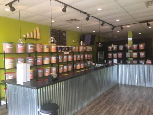 A colorful snack shop interior with bins of various snacks on shelves and a counter in front.