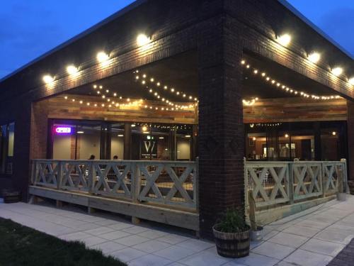 A cozy restaurant exterior at dusk, featuring string lights and a wooden deck with a welcoming atmosphere.