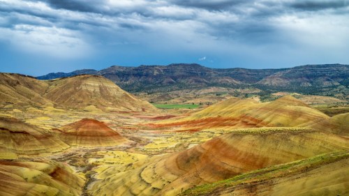 Vibrant, multicolored hills under a cloudy sky, showcasing the unique geological formations of a desert landscape.