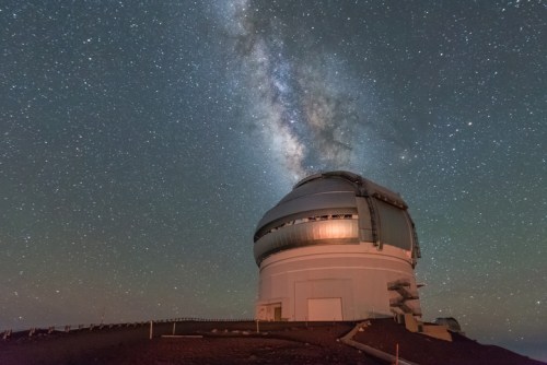A large observatory dome under a starry sky, with the Milky Way prominently visible above it.