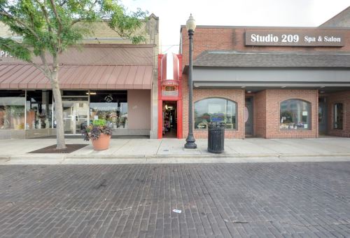 A street view showing two storefronts: a spa and salon on the right and a shop with a striped awning on the left.