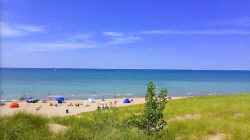 A sunny beach scene with people relaxing, colorful tents, and calm blue waters under a clear sky.