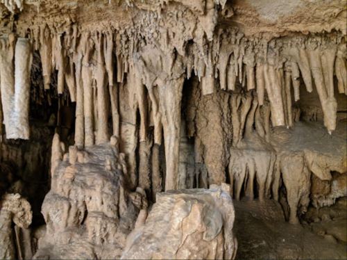 Stalactites and stalagmites in a cave, showcasing intricate rock formations and textures.