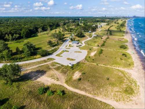 Aerial view of a coastal area with a winding road, sandy beach, and lush greenery along the shoreline.