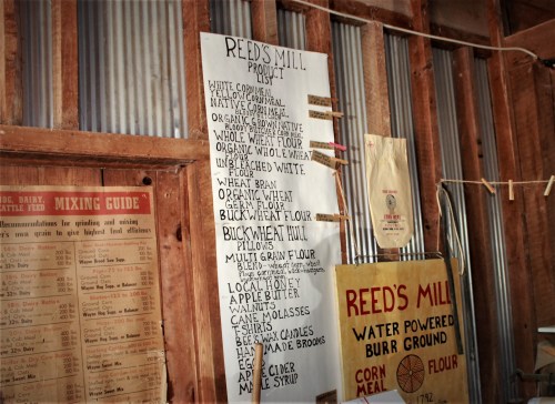 A wall display listing products from Reed's Mill, including various flours, honey, and apple butter.