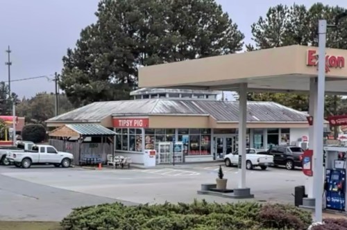 A gas station with a convenience store named "Tipsy Pig" and parked vehicles in the foreground.