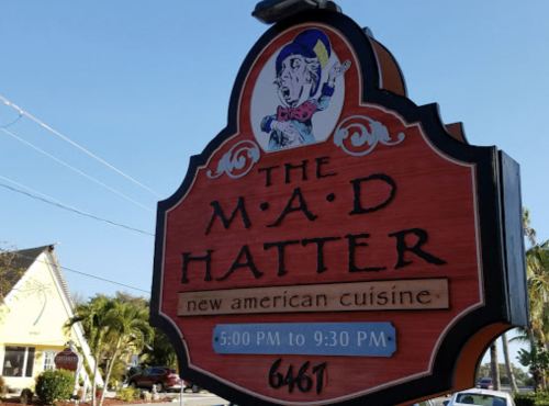 Sign for "The M.A.D. Hatter" restaurant featuring a whimsical design, with hours from 5:00 PM to 9:30 PM.