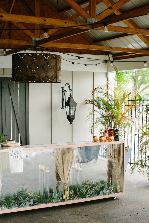 A decorated event space featuring a mirrored table with greenery, candles, and a stylish overhead light fixture.