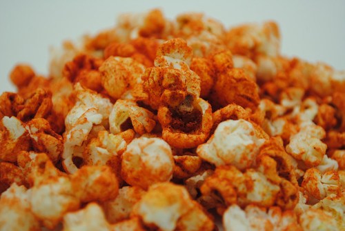 A close-up of a pile of popcorn coated with a vibrant orange seasoning.