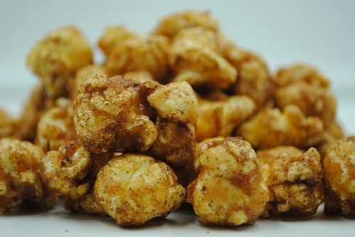A close-up of a pile of caramel popcorn coated with a sprinkle of cinnamon.