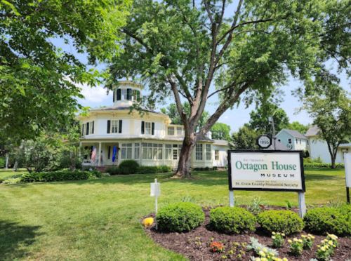 A historic octagonal house museum surrounded by greenery and a sign for the St. Croix County Historical Society.