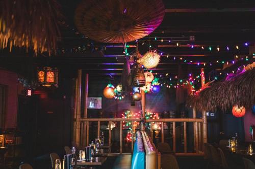 A vibrant restaurant interior with colorful lights, hanging decorations, and a tropical theme.