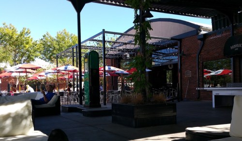 Outdoor dining area with colorful umbrellas, tables, and a relaxed atmosphere under a clear blue sky.