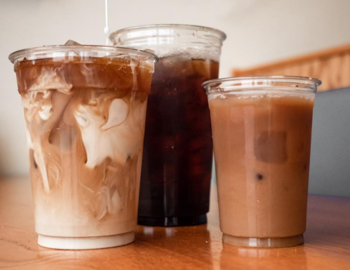 Three cups of iced coffee: one with cream swirling, one dark iced coffee, and a smaller cup of light iced coffee.