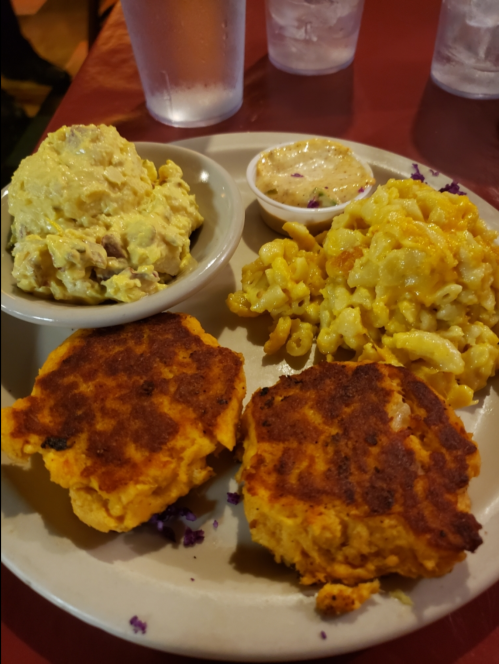 A plate with two golden fritters, macaroni and cheese, and a side of creamy potato salad.