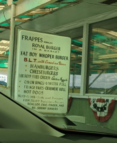 Menu board displaying various burger options, seafood, and sides at a casual dining spot.