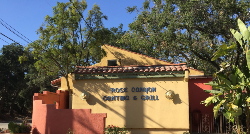 Exterior of Ross Canyon Cantina & Grill, featuring colorful walls and a tiled roof, surrounded by trees.