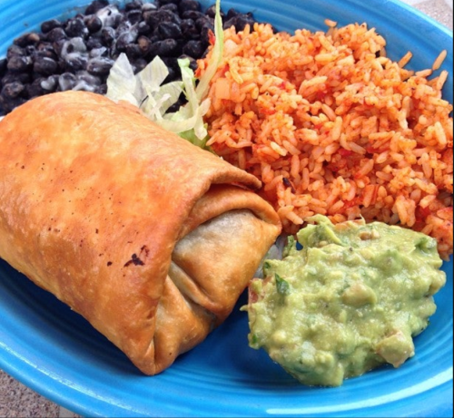 A blue plate with a crispy burrito, black beans, seasoned rice, lettuce, and guacamole.