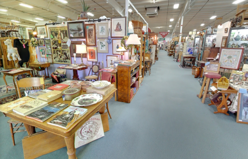 A spacious antique store aisle lined with various vintage items, furniture, and decor on display.