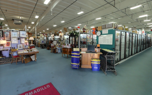 A spacious antique store with various displays, furniture, and collectibles, featuring a checkout area and shopping carts.
