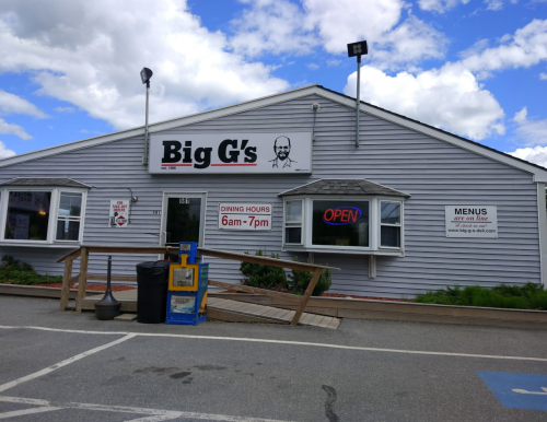 Exterior of Big G's restaurant with a sign showing dining hours and an "Open" notice. Cloudy sky in the background.