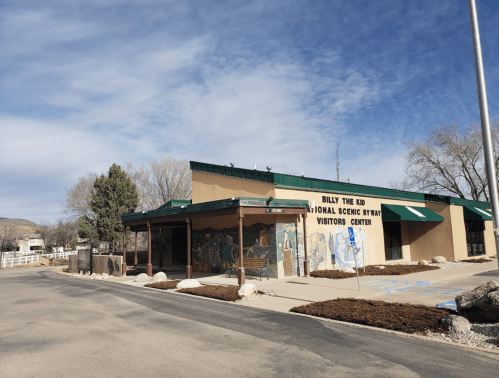 Exterior of the Billy the Kid National Scenic Byway Visitors Center, featuring a mural and a clear blue sky.