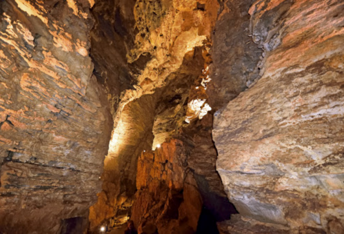 A dimly lit cave interior with rugged rock formations and warm lighting illuminating the walls.