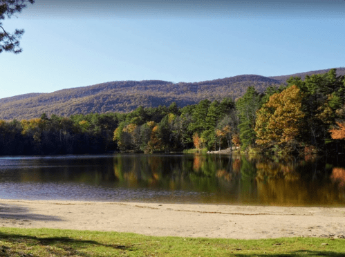 A serene lake surrounded by colorful autumn trees and mountains under a clear blue sky.