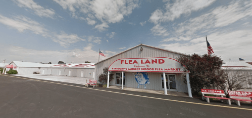 Exterior of Flea Land, Kentucky's largest indoor flea market, featuring a red sign and a clear blue sky.