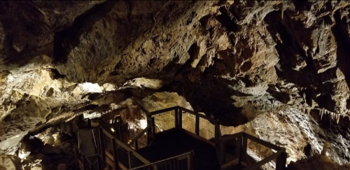 A dimly lit cave interior featuring rocky walls and a wooden observation platform.