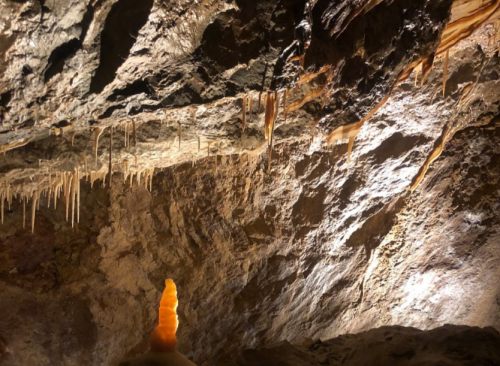 Stalactites and stalagmites in a dimly lit cave, showcasing unique rock formations and textures.