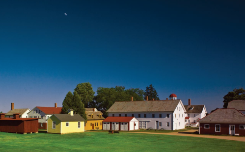 A scenic view of a historic village with colorful buildings under a clear blue sky.