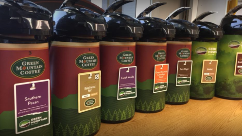 A row of coffee dispensers labeled with various flavors from Green Mountain Coffee, including Southern Pecan and French Vanilla.