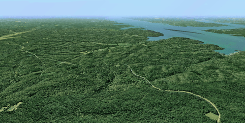 Aerial view of a lush green landscape with winding roads and a large body of water in the distance.