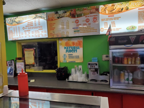 Menu board displaying Jamaican food, natural juices, and smoothies in a colorful restaurant setting.
