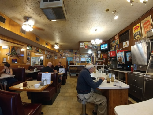 A cozy diner interior with wooden booths, vintage signs, and patrons enjoying their meals at tables.